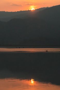 At sunset mountain landscape of silhouette lake reflection.  Sun Setting Behind Mountains. Sunset Over Mountain.