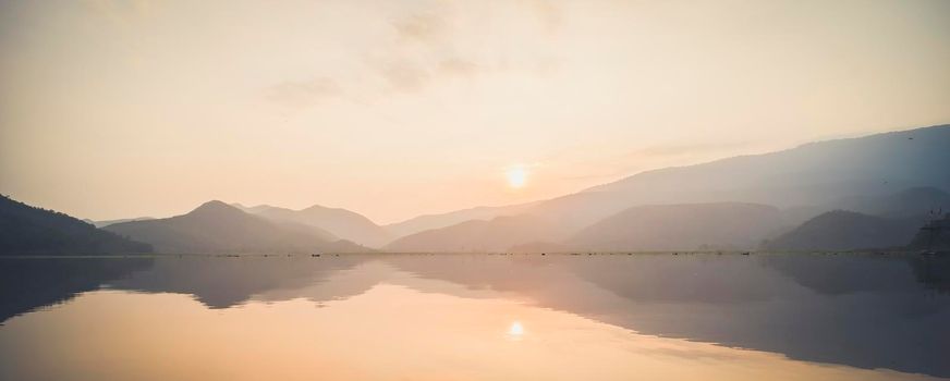 Mountain, sky and river in a quiet and cool atmosphere. Similar color scheme .View of blue mountains with reflection in lake . Landscape with blue mountains near lake in Sukhothai Thailand