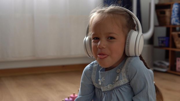 Close up handsome smiling Girl listening music headphones indoor. Children and technology. Love of music, children's dreams hobbies. Talented happy little child leasure. Childhood, musicality, hobby.