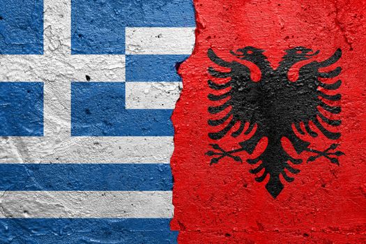 Greece and Albania - Cracked concrete wall painted with a Greek flag on the left and a Albanian flag on the right