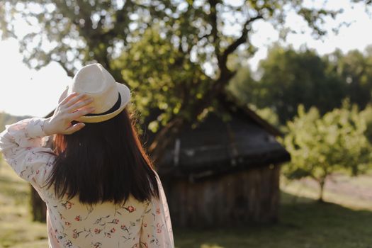 romantic portrait of a young woman in straw hat and beautiful dress in the countryside in summer.