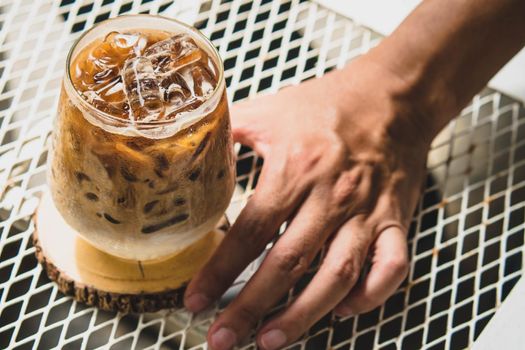 Selective focus Man hold cup of iced coffee. Glass of Cold Coffee with Milk on Table for summertime, selective focus.