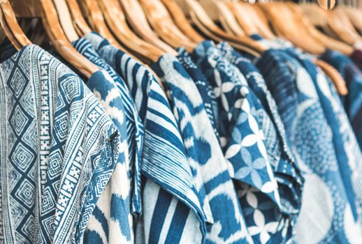 Selective focus tie dye shirts in blue white clothing hanging on rack.