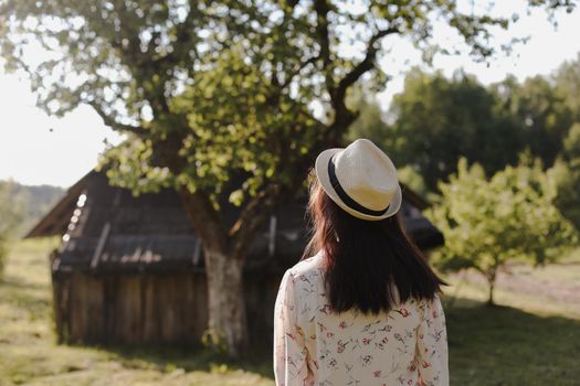 romantic portrait of a young woman in straw hat and beautiful dress in the countryside in summer.