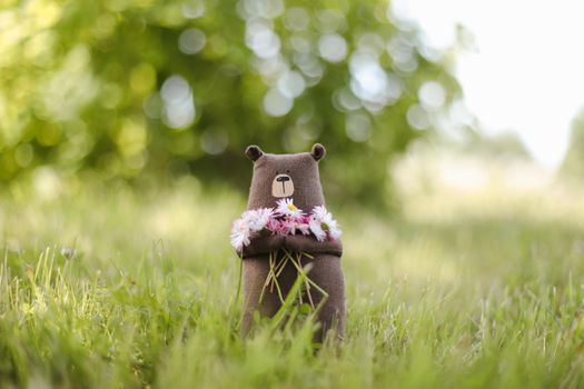 Eco-friendly cute handmade toy bear on grass at sunny summer day