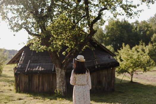 romantic portrait of a young woman in straw hat and beautiful dress in the countryside in summer.