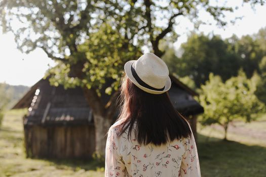 romantic portrait of a young woman in straw hat and beautiful dress in the countryside in summer.