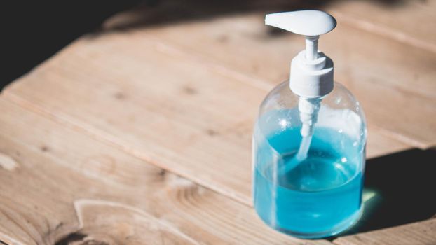 soft focus alcohol hand gel bottle with pump top. Hand Sanitizer Dispenser on wooden table.