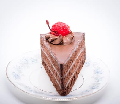 Chocolate cake with topping cherry in ceramic plate. Delicious cuisine dessert over white background