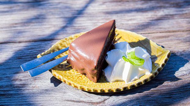 chocolate fudge cake serve with cream on vintage wooden table.