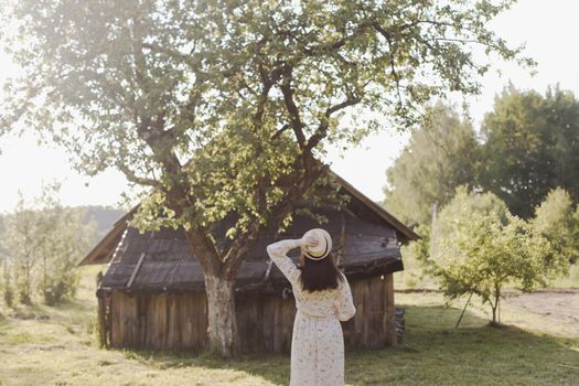 romantic portrait of a young woman in straw hat and beautiful dress in the countryside in summer.