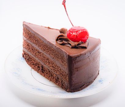 Chocolate cake with topping cherry in ceramic plate. Delicious cuisine dessert over white background