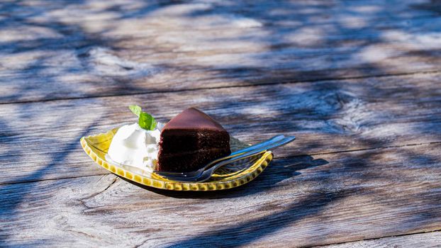 chocolate fudge cake serve with cream on vintage wooden table.