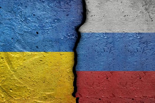 Ukraine and Russia - Cracked concrete wall painted with a Ukrainian flag on the left and a Russian flag on the right