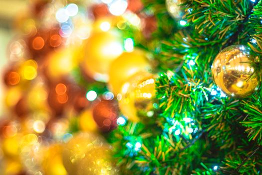 Selective focus Christmas tree with holiday gold ball and lights with copy space on blurred bokeh background.