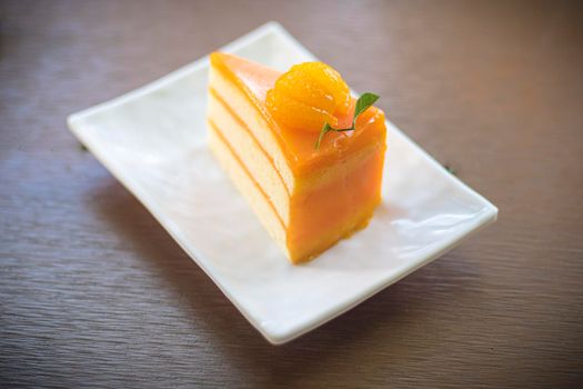 close up fruit orange jam cream cake dessert sweet on ceramic plate.