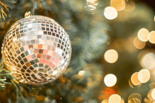 Selective focus Christmas tree with holiday silver disco balls and lights with copy space on blurred bokeh background.