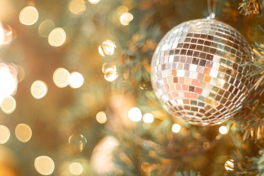 Selective focus Christmas tree with holiday silver disco balls and lights with copy space on blurred bokeh background.