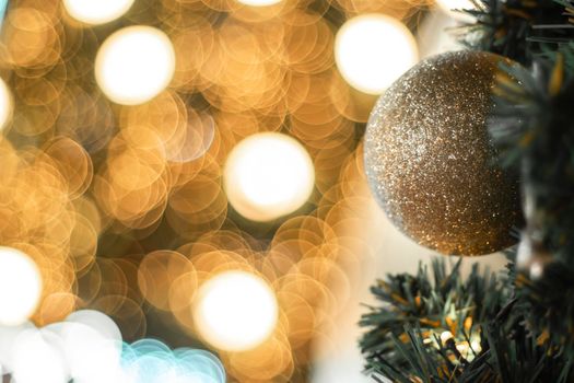Selective focus Christmas tree with holiday gold ball and lights with copy space on blurred bokeh background.