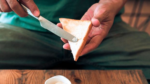 Man spreading butter on the bread with Pan Fried Egg with Toppings