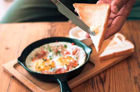 Man spreading butter on the bread with Pan Fried Egg with Toppings