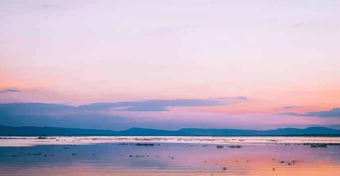 Panorama lake and mountain landscape at sunset with pink sky