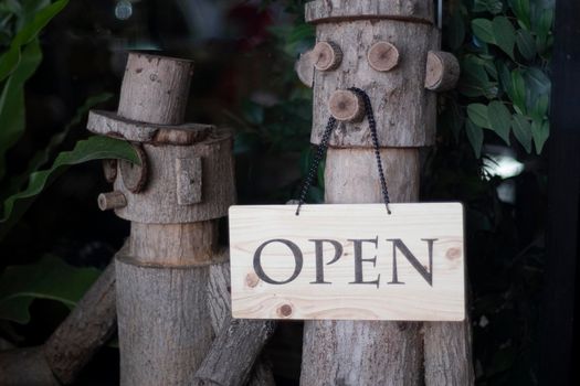 Open Sign Hanging on wooden doll in front of entrance door for decoration cafe restuarant.