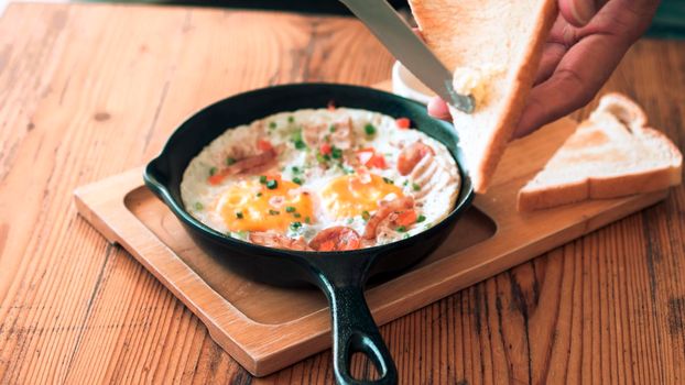 Man spreading butter on the bread with Pan Fried Egg with Toppings