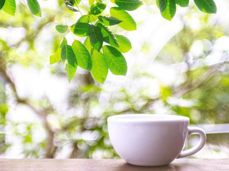 A white coffee mug placed on a wooden table in a natural