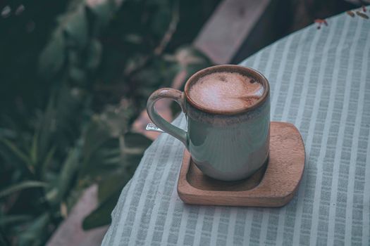 Cup of coffee latte with heart shape on old wooden background in the morning sunlight
