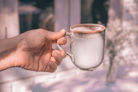 Hands of a man or barista holding cup of hot coffee latte with heart shaped foam art