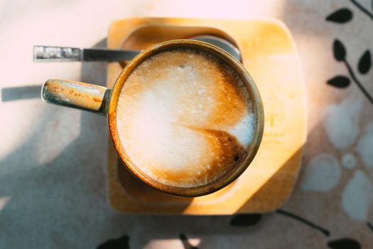 Cup of coffee latte in green poetry mug on old wooden background in the morning sunlight