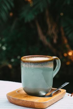 Cup of coffee latte in green poetry mug on old wooden background in the morning sunlight