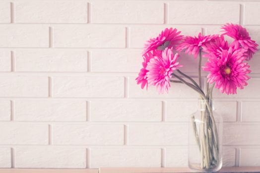 Soft focus Pink Gerbera Daisies in Glass Vase on white brick wall texture background with copy space.