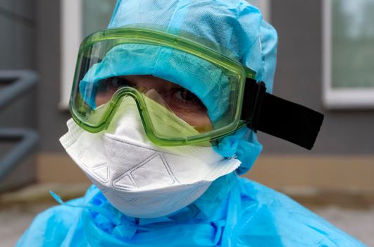 A doctor in a disposable antiepidemic suit in a mask and glasses.