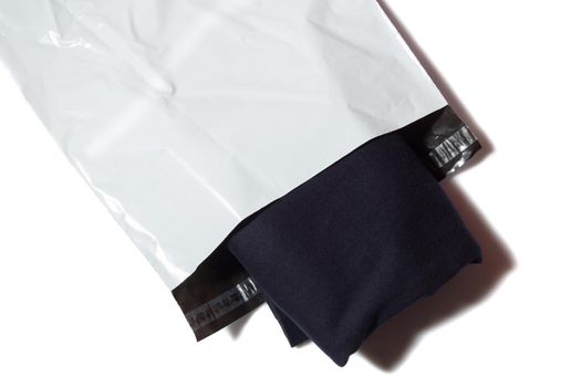 Blue jumper in white plastic mailing bag on white background