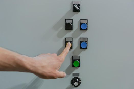 Male engineer worker turns on the buttons on the control panel photo close up of a male hand