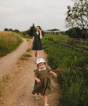 Happy family, active mother with little child, adorable toddler girl. Happy mom is playing with a toddler girl outdoors in summer.