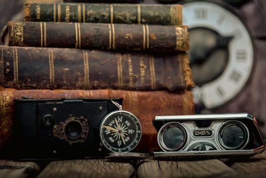 Pocket watch, blur stack of old book, hourglass, vintage binocular and world desk globe on dark background. Journey and Learning Concept, Vintage Style