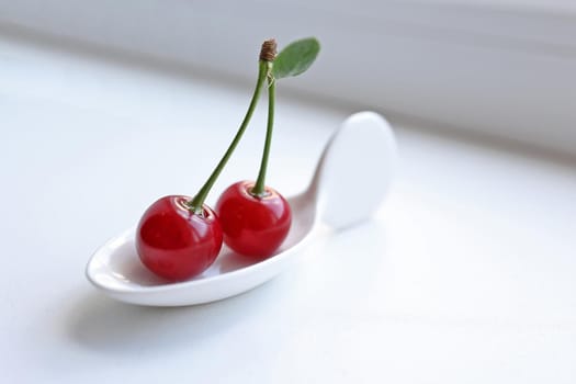 couple of cherries on a white miniature plate. Copy space. Minimal diet concept, minimalism, selective focus