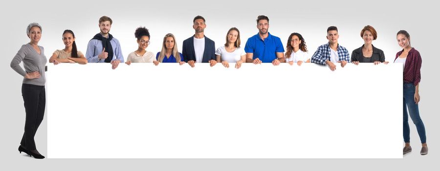 Group of hapy people standing together and holding a blank sign for your text, isolated white background