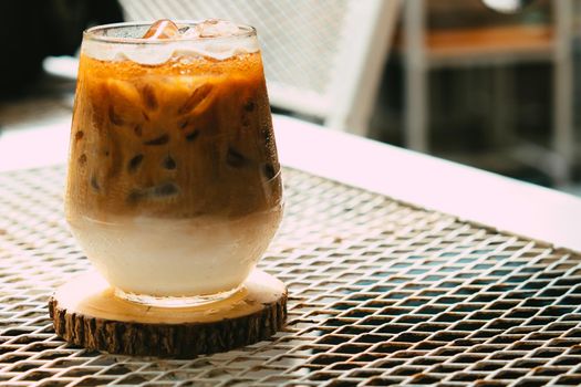 Iced latte coffee in a glass with cream on bottom . cold summer drink background