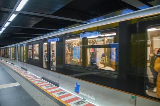 Brussels, Belgium - 01.31.2022 A young woman enters a subway car in a big city on a platform while masked people sit there. High quality photo