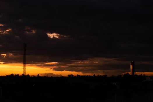 Panorama Cityscape at sunset with large river at foreground and strom clouds at background in Thailand.