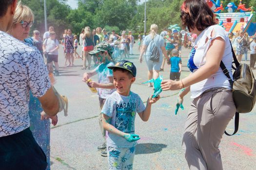 Novokuznetsk, Kemerovo region, Russia - June 12, 2022 :: Happy family with colorful faces painted with holi powder having fun outdoors.