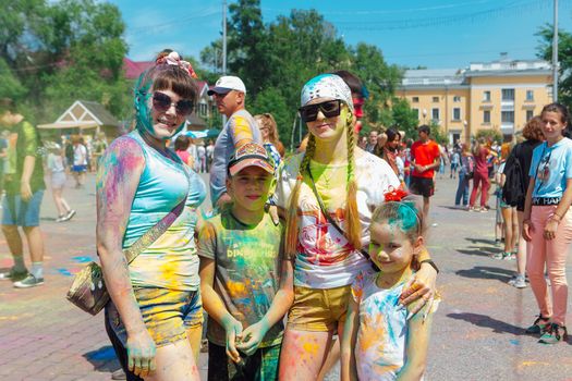 Novokuznetsk, Kemerovo region, Russia - June 12, 2022 :: Happy family with colorful faces painted with holi powder having fun outdoors.