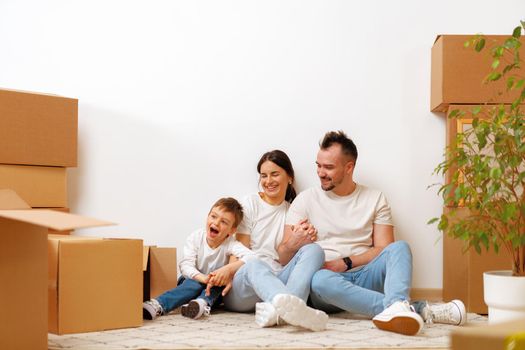 Young parents and son having fun during moving day to new house, portrait