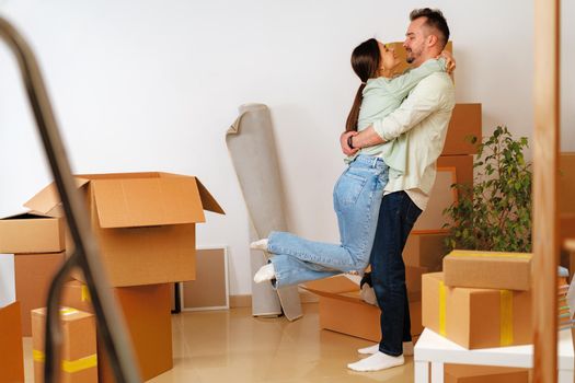 Young happy couple in room with lots of moving boxes at new home