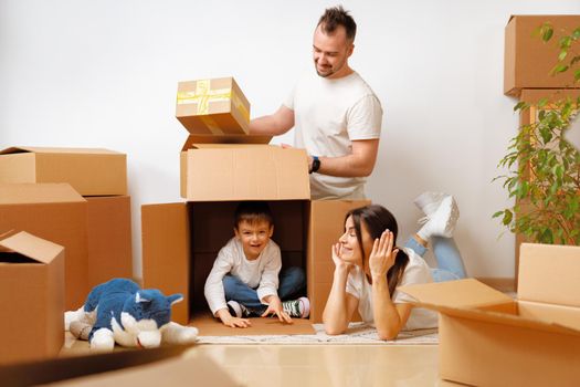 Young parents and son having fun during moving day to new house, portrait