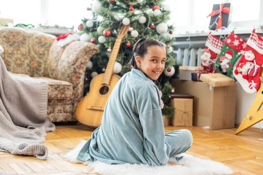 Merry Christmas and Happy Holidays. Cute little child girl is decorating the Christmas tree indoors